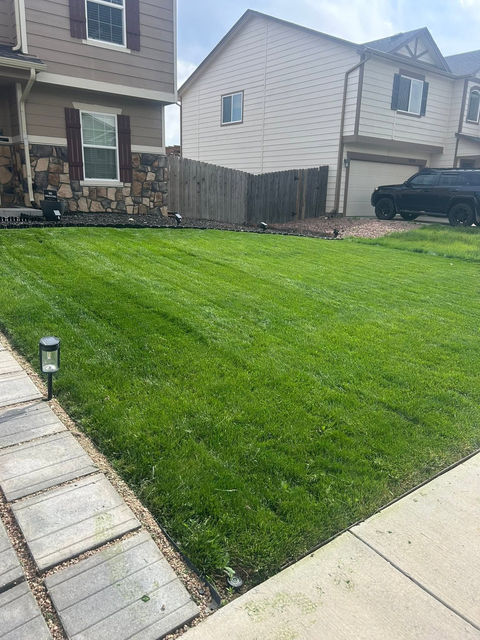Finished residential yard with lush striped lawn and concrete pathway